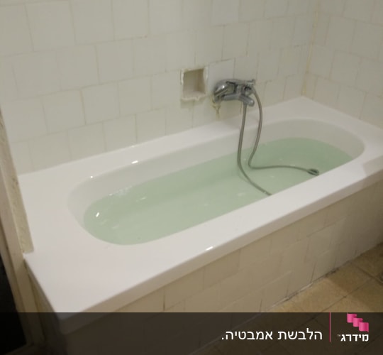 אמבטיה עם חיפוי אריחים לבנים וברז מותקן
